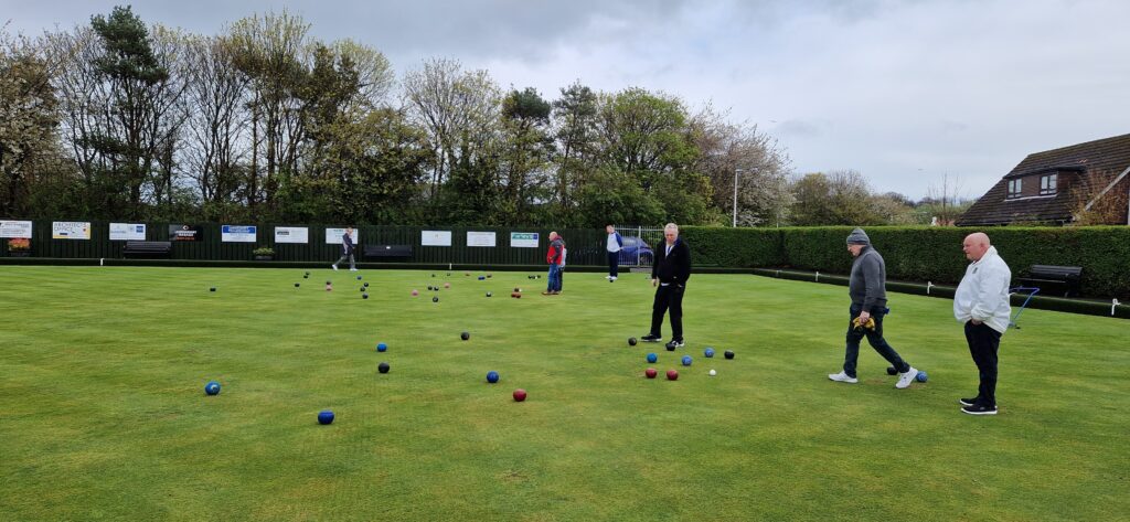 People playing bowls on a lawn with a green field at Longniddry Bowling Club